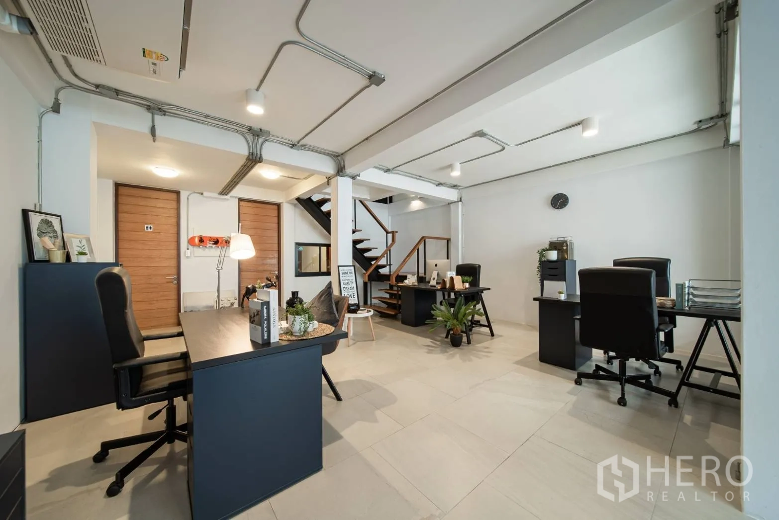 Townhouse for rent in Watthana, Bangkok - Spacious workspace level with several desks, wooden doors and a central staircase.