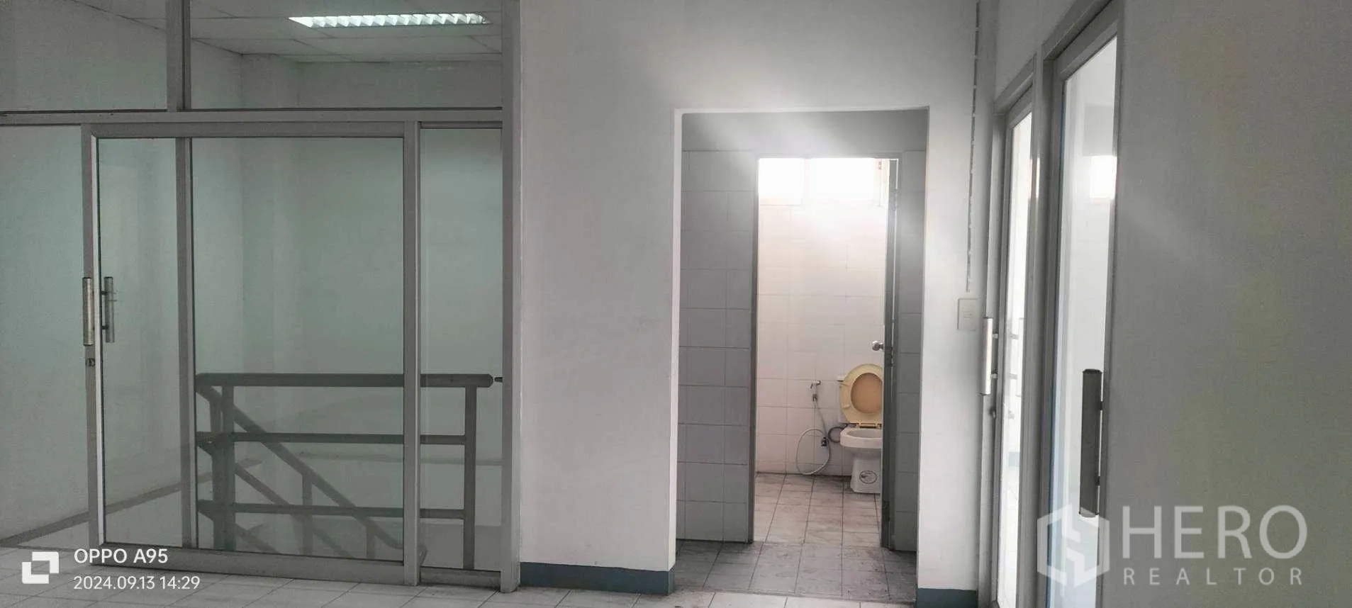 Factory for rent in Khlong Luang, Pathum Thani - Upper floor corridor with glass partitions and a restroom doorway.
