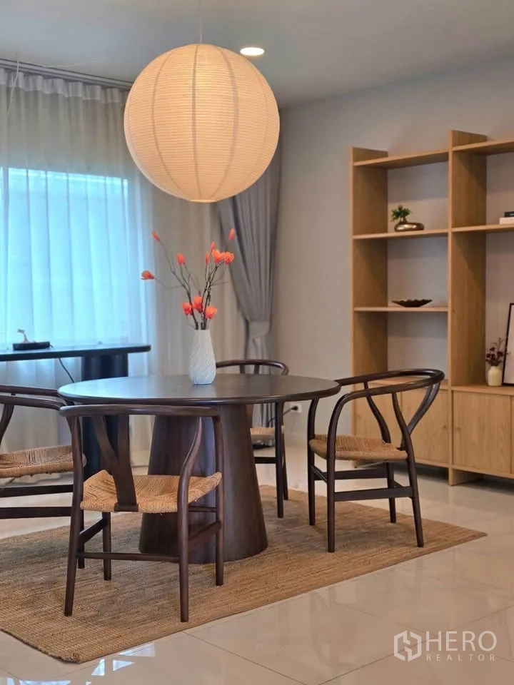 Detached House for rent or sale in Bang Phli, Samut Prakan - Dining corner with round table, pendant light, and wood shelving unit.