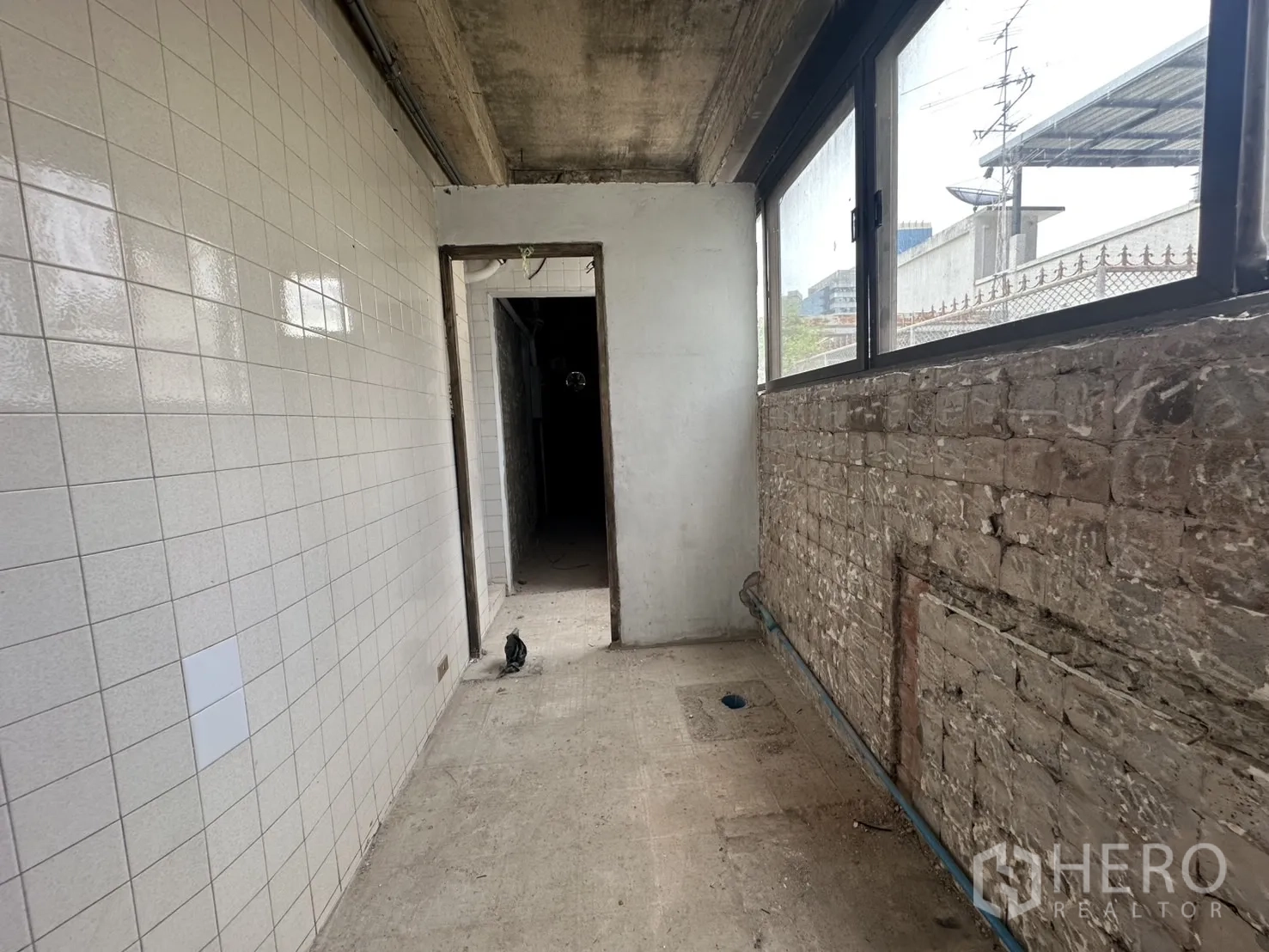 零售空间 出租在Bang Rak, Bangkok - 长走廊带白色瓷砖墙、排水点与管线预留。