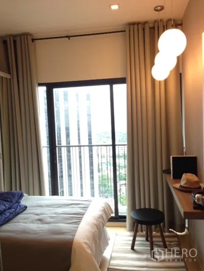 Condominium for rent in Phaya Thai, Bangkok - Cozy bedroom with floor-to-ceiling sliding door to a balcony, draped curtains and globe pendant lights.