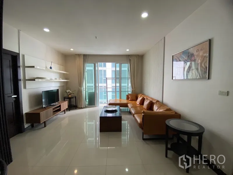公寓 出租在Watthana, Bangkok - 客厅宽景，电视柜与开放层架、筒灯天花，落地窗通往阳台与橙色沙发。