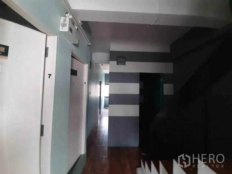 店屋 出租在Watthana, Bangkok - 走廊内有编号白门与楼梯，条纹装饰墙