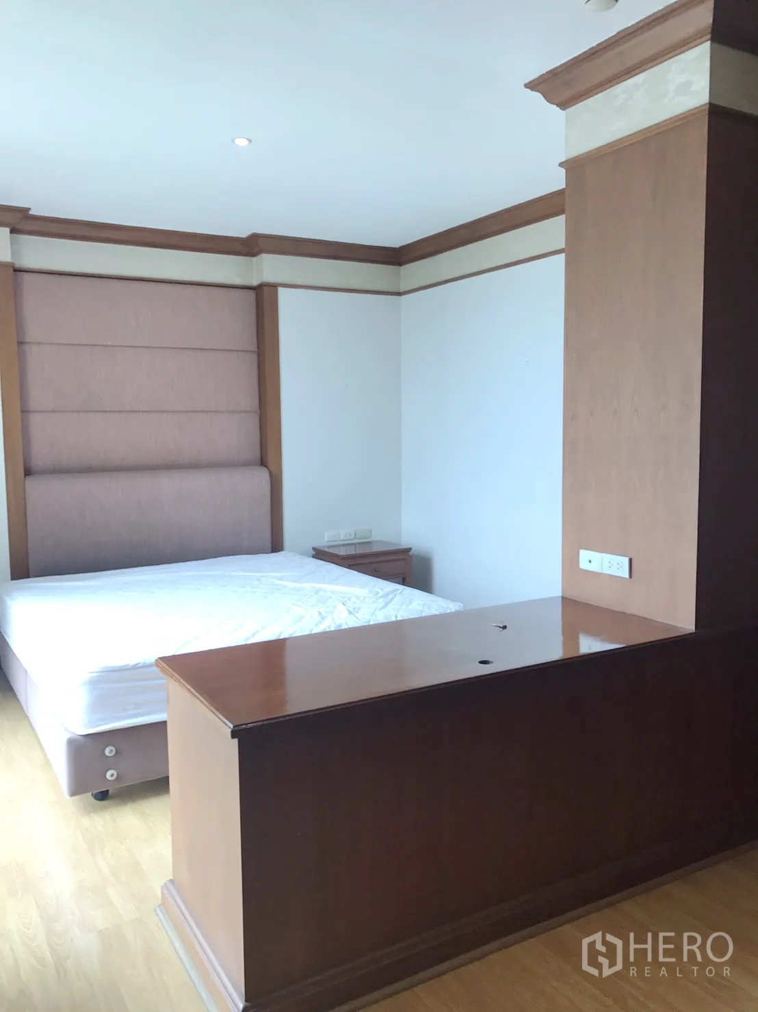 Condominium for rent in Pathum Wan, Bangkok - Bedroom with upholstered headboard, warm wood trim, and ample natural light.