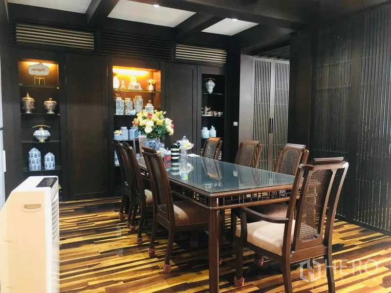 Townhouse for rent in Yan Nawa, Bangkok - Formal dining room with a glass-top table, built-in illuminated display cabinets, and wood accents.
