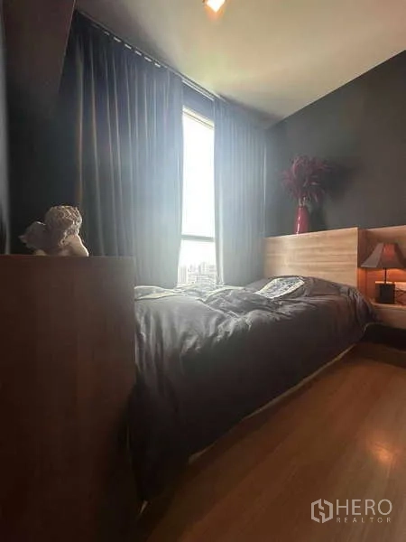 Condominium for sale in Phaya Thai, Bangkok - Second bedroom with large window, bedside lamp, and city outlook.