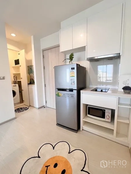 Condominium for rent or sale in Khlong Toei, Bangkok - Kitchen with stainless refrigerator, electric cooktop, microwave and access to laundry nook.