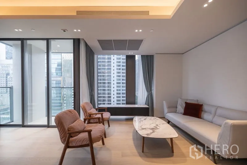 Condominium for rent in Pathum Wan, Bangkok - Bright living room with marble coffee table, sofa set and curtain-framed skyline outlook.