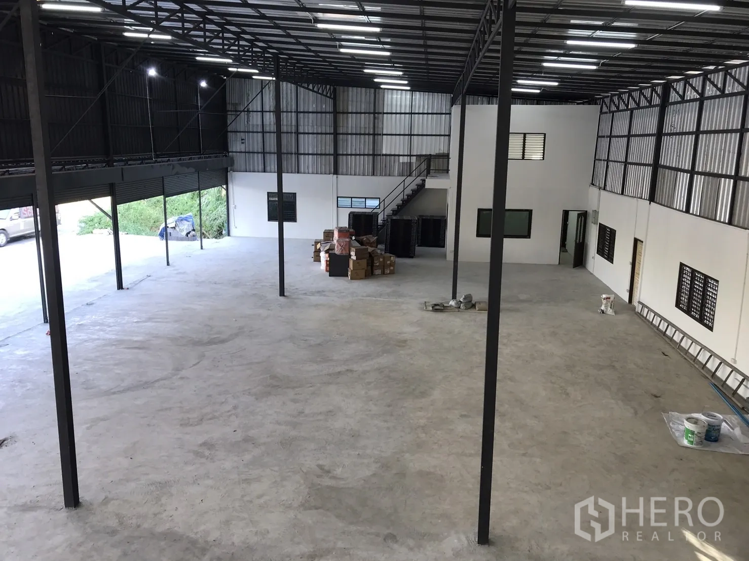 Warehouse for rent in Lam Luk Ka, Pathum Thani - Wide-angle interior showing warehouse columns, lighting and partitioned rooms.