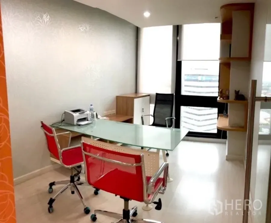 Office Space for rent in Bang Na, Bangkok - Fitted private office with glass desk, red chairs and a floor-to-ceiling window with city view.