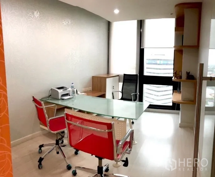 Office Space for rent in Bang Na, Bangkok - Fitted private office with glass desk, red chairs and a floor-to-ceiling window with city view.