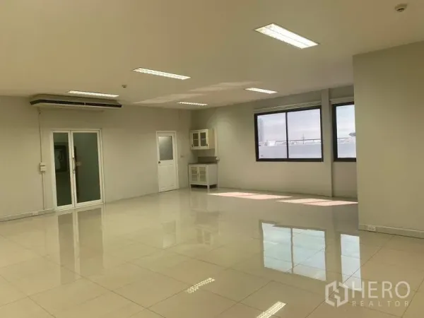办公空间 出租在Bang Na, Bangkok - 明亮的开放式办公室，亮面瓷砖地面，大窗户、茶水柜和玻璃门。