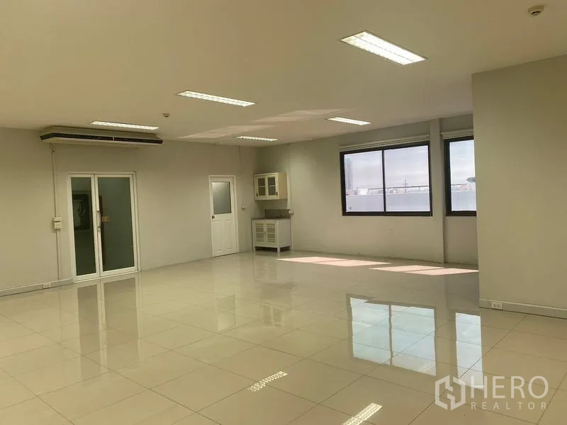 办公空间 出租在Bang Na, Bangkok - 明亮的开放式办公室，亮面瓷砖地面，大窗户、茶水柜和玻璃门。