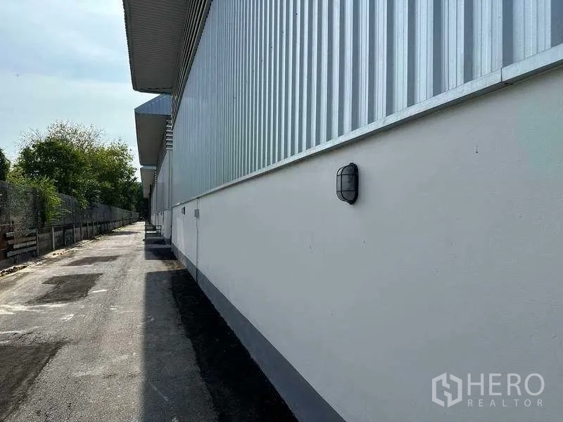 Factory for rent in Bang Sao Thong, Samut Prakan - Service lane running along the side of the factory with exterior wall lighting.