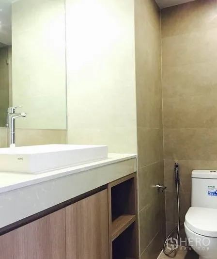 คอนโด ให้เช่าในWatthana, Bangkok - ห้องน้ำพร้อมอ่างล้างหน้าแบบวางบนเคาน์เตอร์ กระจกบานใหญ่ ตู้ไม้ และโถสุขภัณฑ์