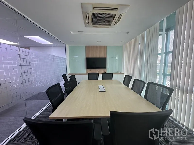 Office Space for rent - Row of compact cubicles with blue panels situated beside windows with sheer blinds.