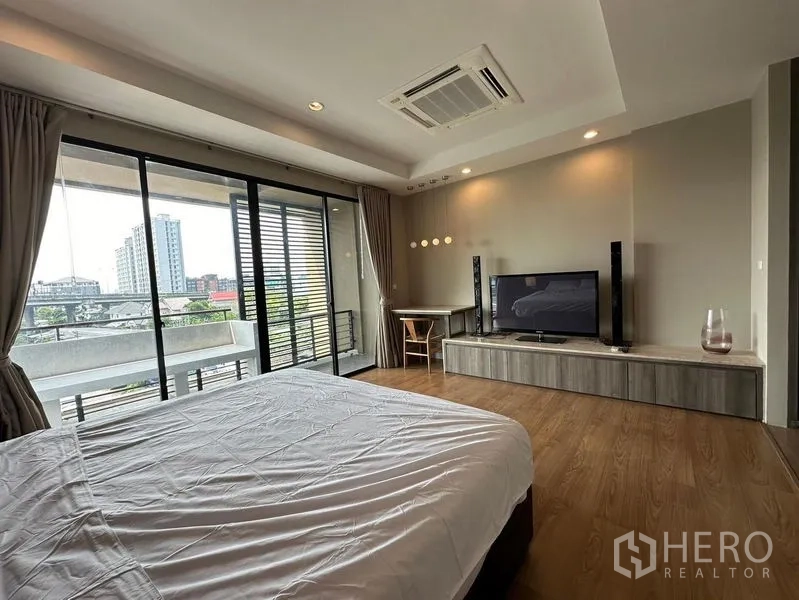 联排别墅 出租在Khlong Toei, Bangkok - 主卧另一角度，展示影音墙、书桌与推拉门通往露台。
