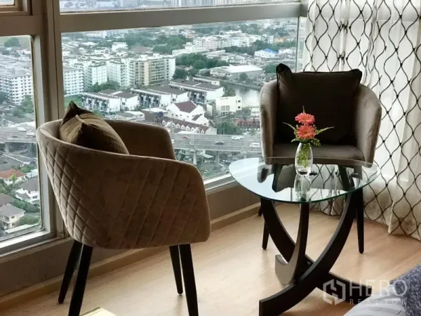 Condominium for rent in Khlong Toei, Bangkok - Window nook with two armchairs and round glass table overlooking the city.