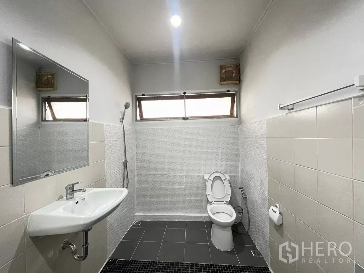 Home Office for rent in Din Daeng, Bangkok - Tiled bathroom featuring a shower zone, wall‑hung sink and toilet beneath clerestory windows.