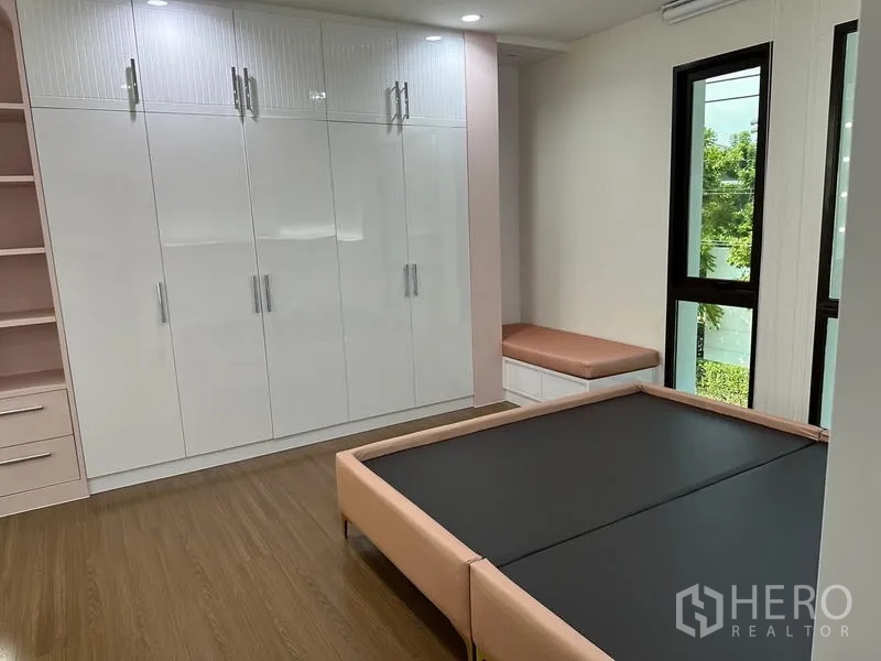 Detached House for sale in Saphan Sung, Bangkok - Bedroom with built-in white wardrobes, window seat and platform bed.