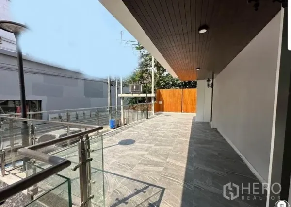 Retail Space for rent - Corner plaza area with glass railing, wooden privacy fence and grey stone tiles ideal for display or seating.