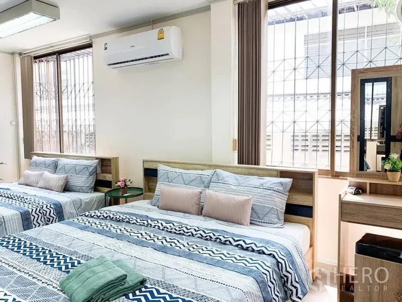 Home Office for rent in Khlong Toei, Bangkok - Airy bedroom with two queen beds, big windows, blinds and a small vanity.
