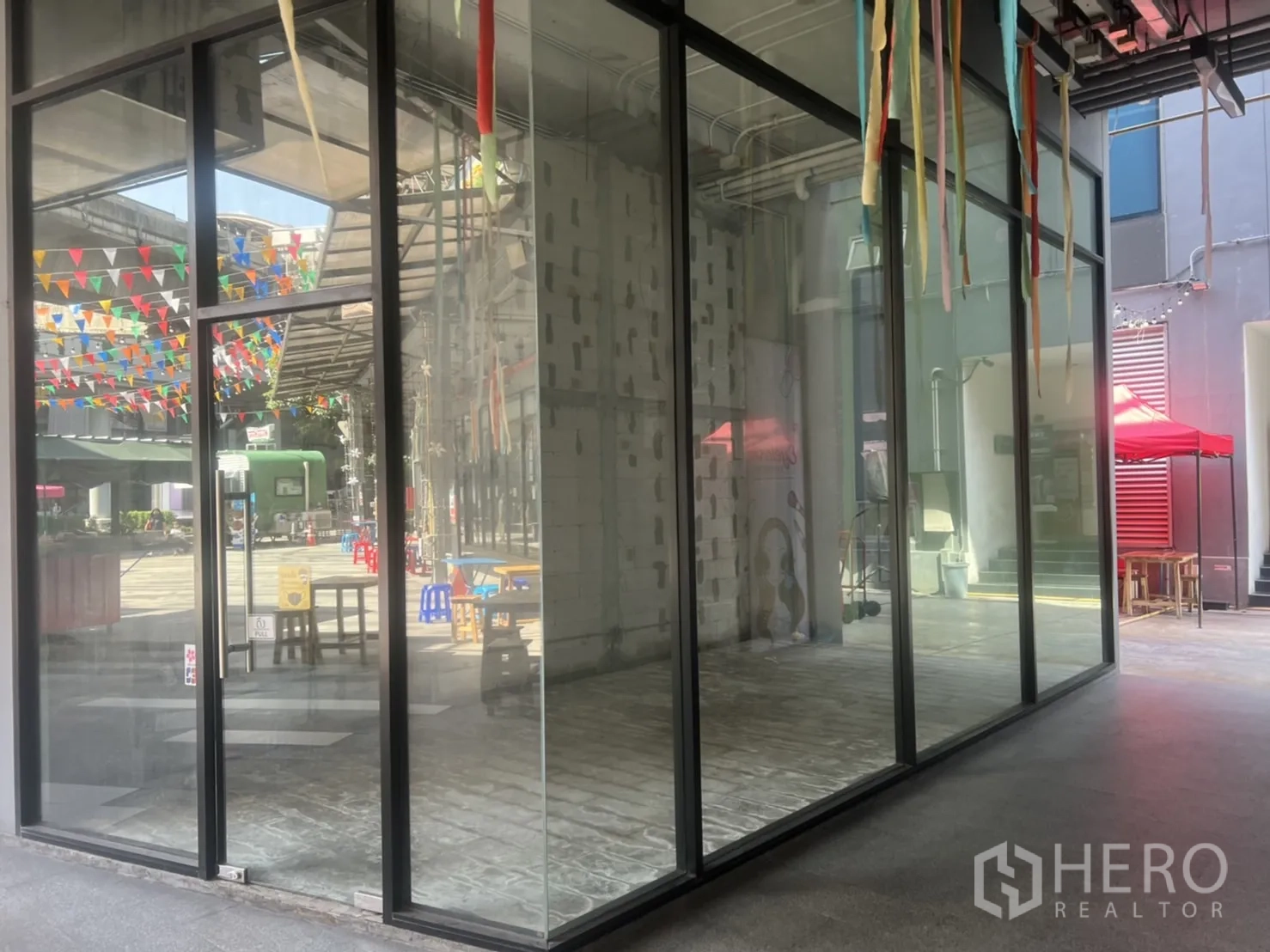 Retail Space for rent in Khlong Toei, Bangkok - Corner retail unit with floor-to-ceiling glass frontage facing an open plaza in Phra Khanong.