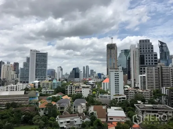 公寓 出售在Khlong Toei, Bangkok - 曼谷城市天际线，高楼与绿意低密社区相映成景。