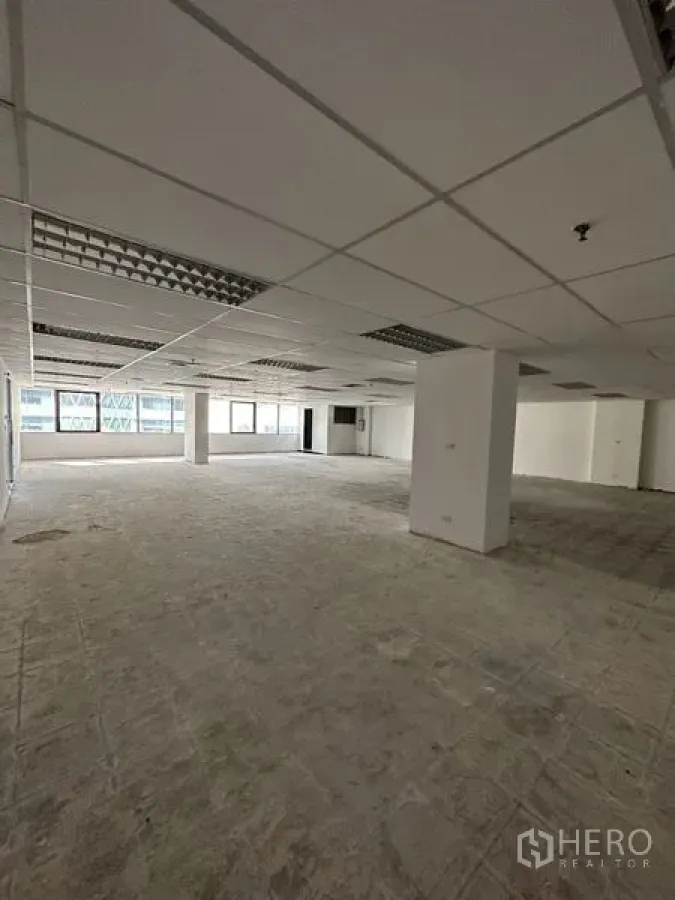 Office Space for rent in Pathum Wan, Bangkok - Spacious columned office interior with wide windows and raw concrete subfloor.