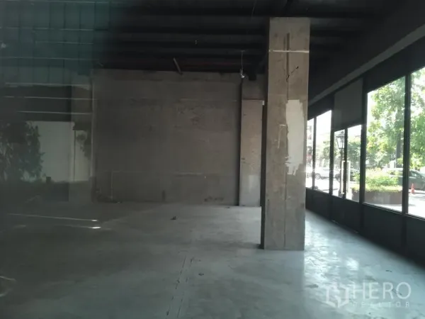 零售空间 出租在Khlong Toei, Bangkok - 宽敞店铺空间，中央立柱，临街落地玻璃门面与街侧绿植。