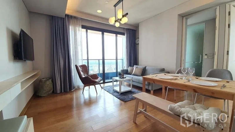 公寓 出租在Khlong Toei, Bangkok - 客餐厅一体，木地板，现代灯具，落地玻璃门通向阳台。