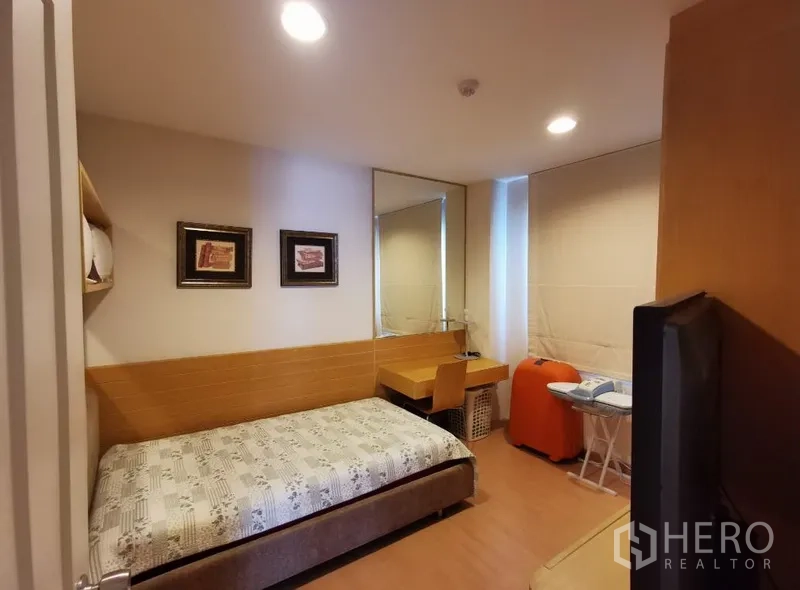 Condominium for sale in Sathon, Bangkok - Second bedroom with single bed, study desk, wall mirror and blackout blinds.