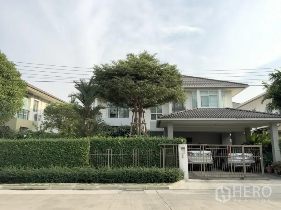 Detached House for sale in Khan Na Yao, Bangkok - Two-storey detached house with lush hedge, large tree, gated entrance and covered two-car carport in a quiet Khan Na Yao neighborhood.