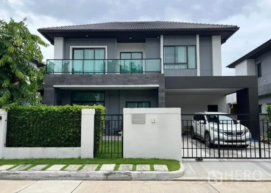 Detached House for sale in Khan Na Yao, Bangkok - Front elevation of a two-storey detached house with secure fence and carport.
