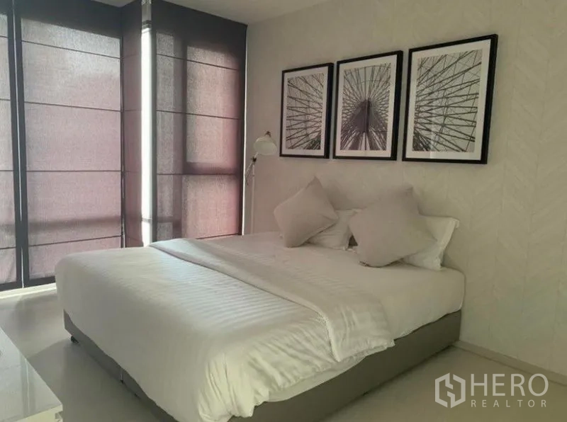 公寓 出租在Khlong Toei, Bangkok - 卧室设特大床、床侧立灯与三幅装饰画，配遮光百叶帘。