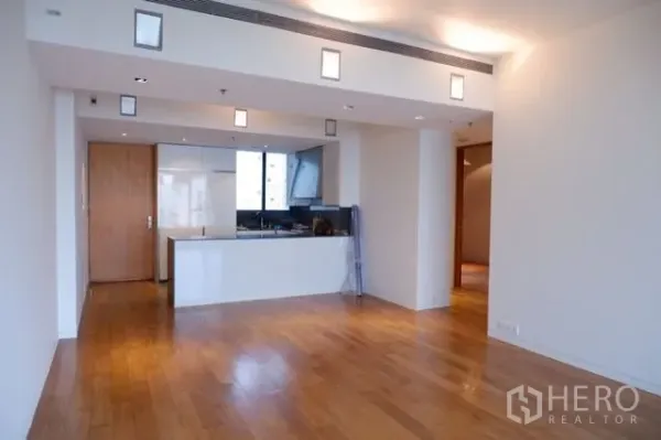 Condominium for sale in Sathon, Bangkok - Open-plan living area with hardwood floors and a sleek white kitchen island.