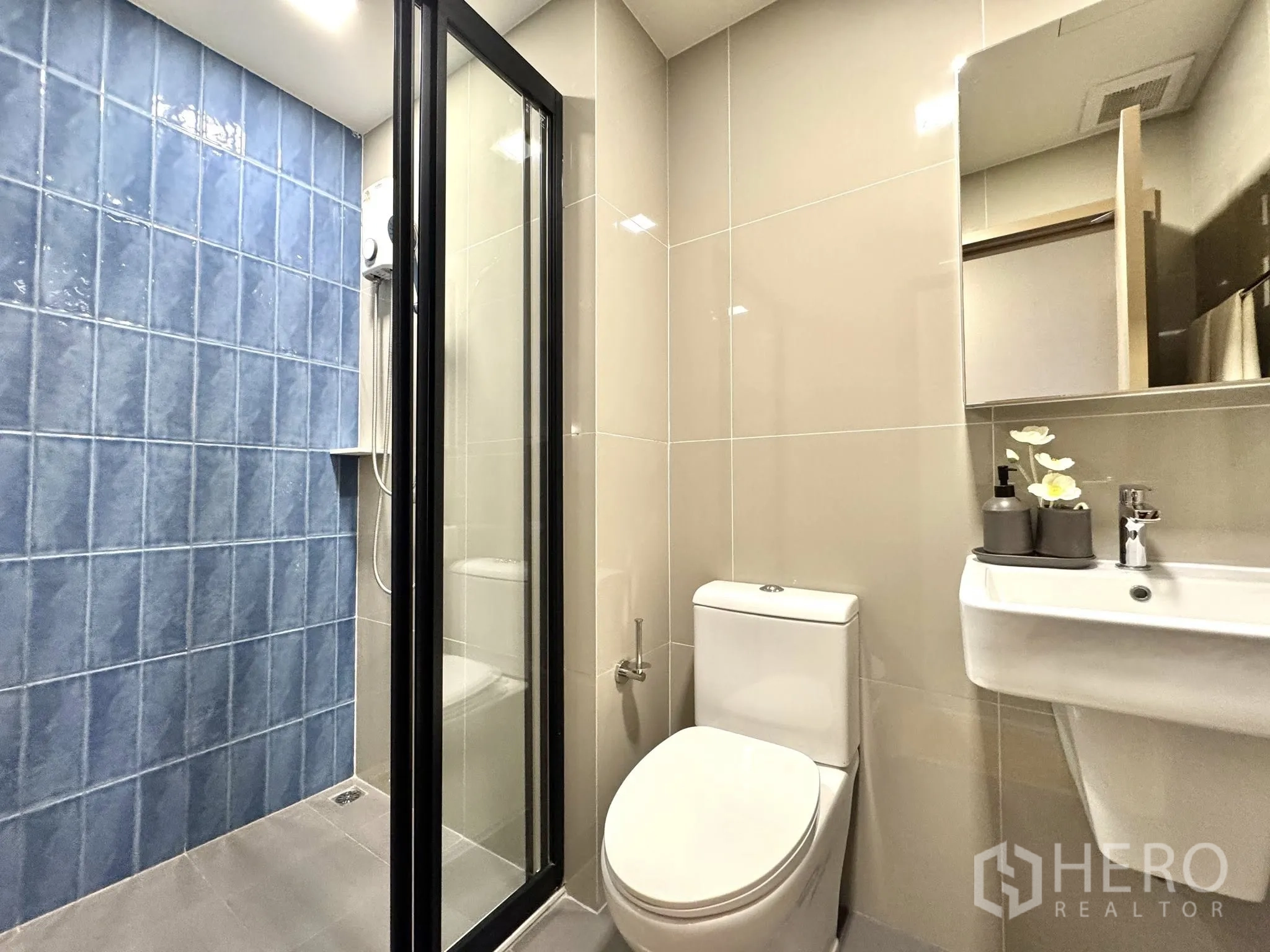 Condominium for rent in Watthana, Bangkok - Second bathroom with sliding glass shower door, blue tiles, toilet, and mirror.
