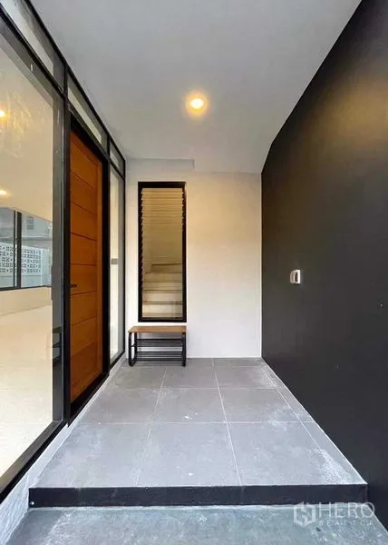 带办公室的家 出售在Lat Phrao, Bangkok - 有顶门廊，长椅与木门旁的整面玻璃