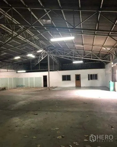 Warehouse for rent in Khan Na Yao, Bangkok - Spacious warehouse interior with high steel truss roof and bright fluorescent lighting.