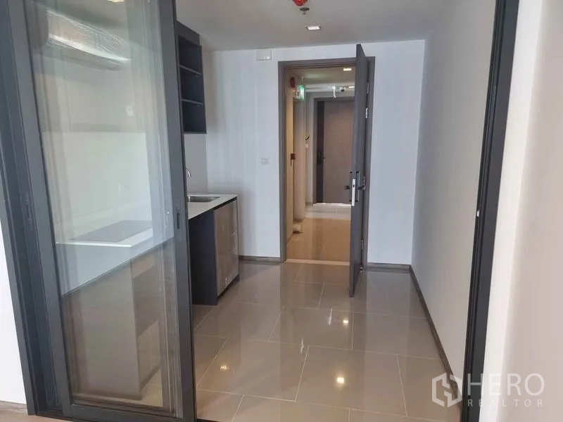 Condominium for sale in Phaya Thai, Bangkok - Entry corridor leading to a kitchenette with cabinets and sink.