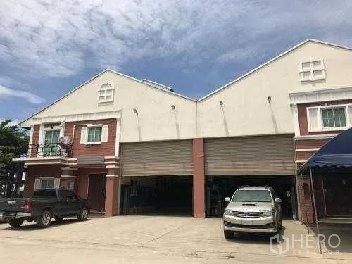 Warehouse for rent in Samut Sakhon - Twin-bay warehouse facade with high roller shutters and parking area.