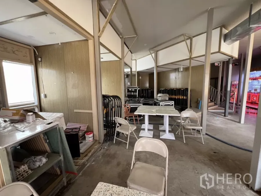 零售空间 出租在Khlong Toei, Bangkok - 半装修的零售室内，开放式布局，隔断框架、露石台面桌、折叠椅与水泥地面。