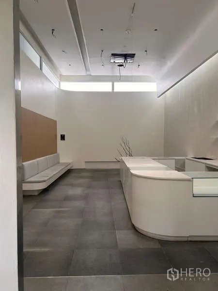 Standalone for rent in Khlong Toei, Bangkok - Minimalist reception area with built-in bench seating and a curved counter.