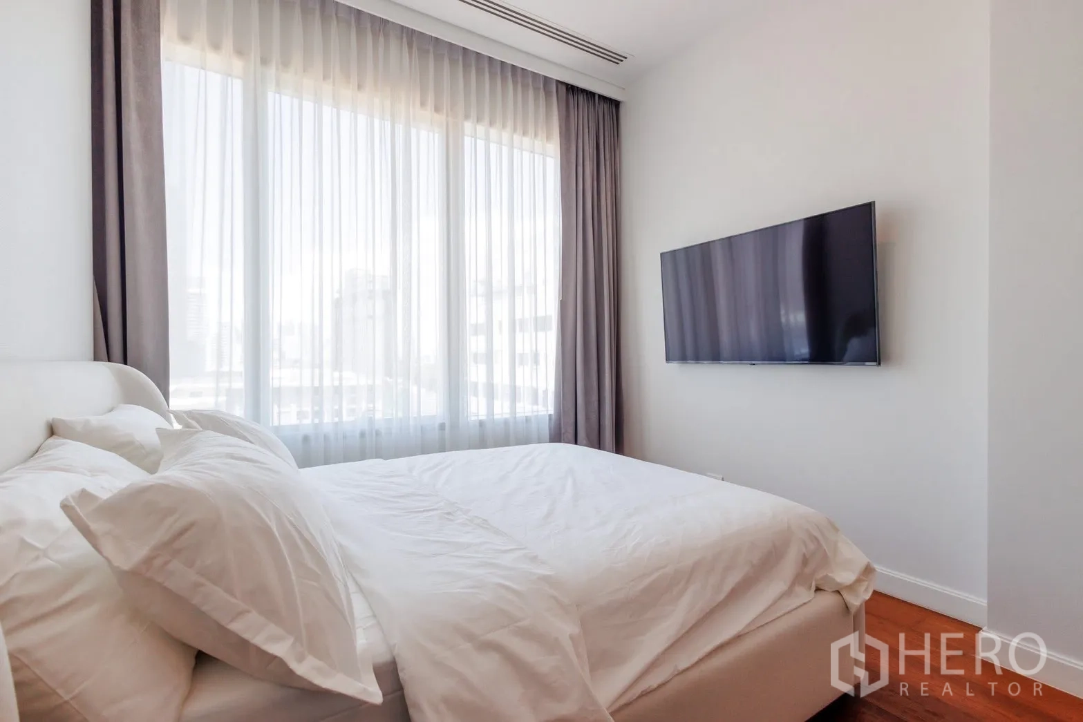 คอนโด for rent or sale in Pathum Wan, Bangkok - ห้องนอนสว่างพร้อมหน้าต่างบานใหญ่ ผ้าม่านโปร่ง และทีวีติดผนัง