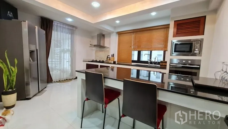 Detached House for rent in Saphan Sung, Bangkok - Modern kitchen with breakfast bar, gas hob, and range hood.