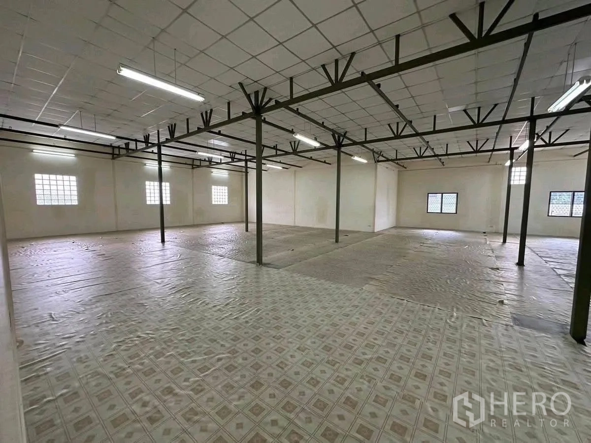 Warehouse for rent in Lat Phrao, Bangkok - Expansive storage floor with steel columns, grid ceiling and strip lighting.