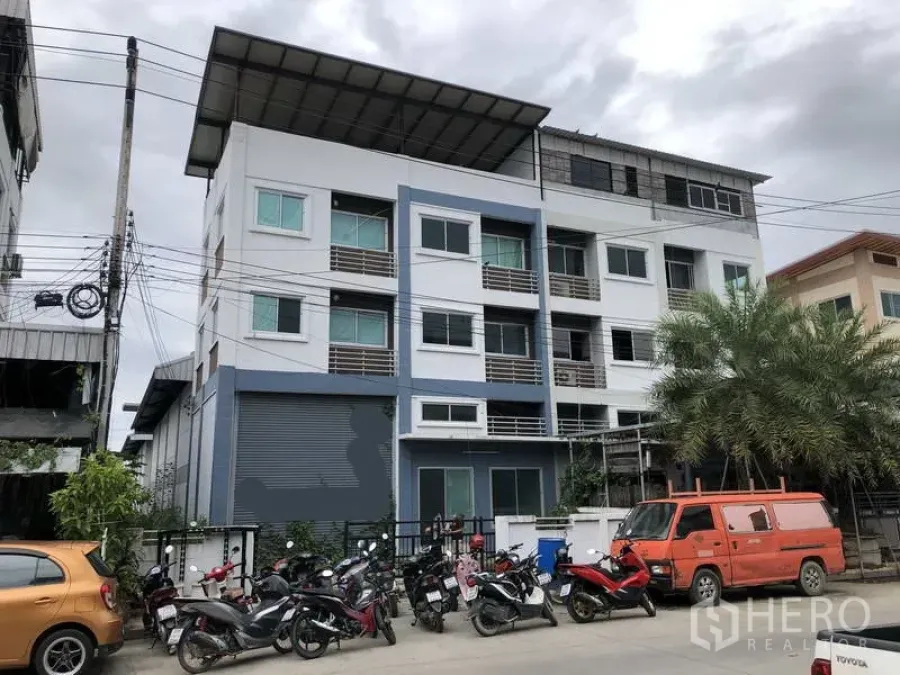 货栈 出租在Lat Lum Kaeo, Pathum Thani - 仓库/办公楼外立面街景，带卷帘门与停车位。