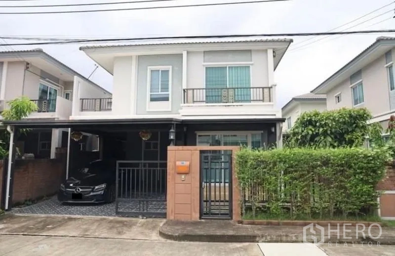 独立式住宅 出租在Suan Luang, Bangkok - 两层独栋别墅正面，带入户大门、覆盖车棚与小花园。
