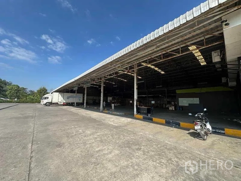 Warehouse for rent in Lam Luk Ka, Pathum Thani - Open loading canopy showing truck access and partially open warehouse interior.