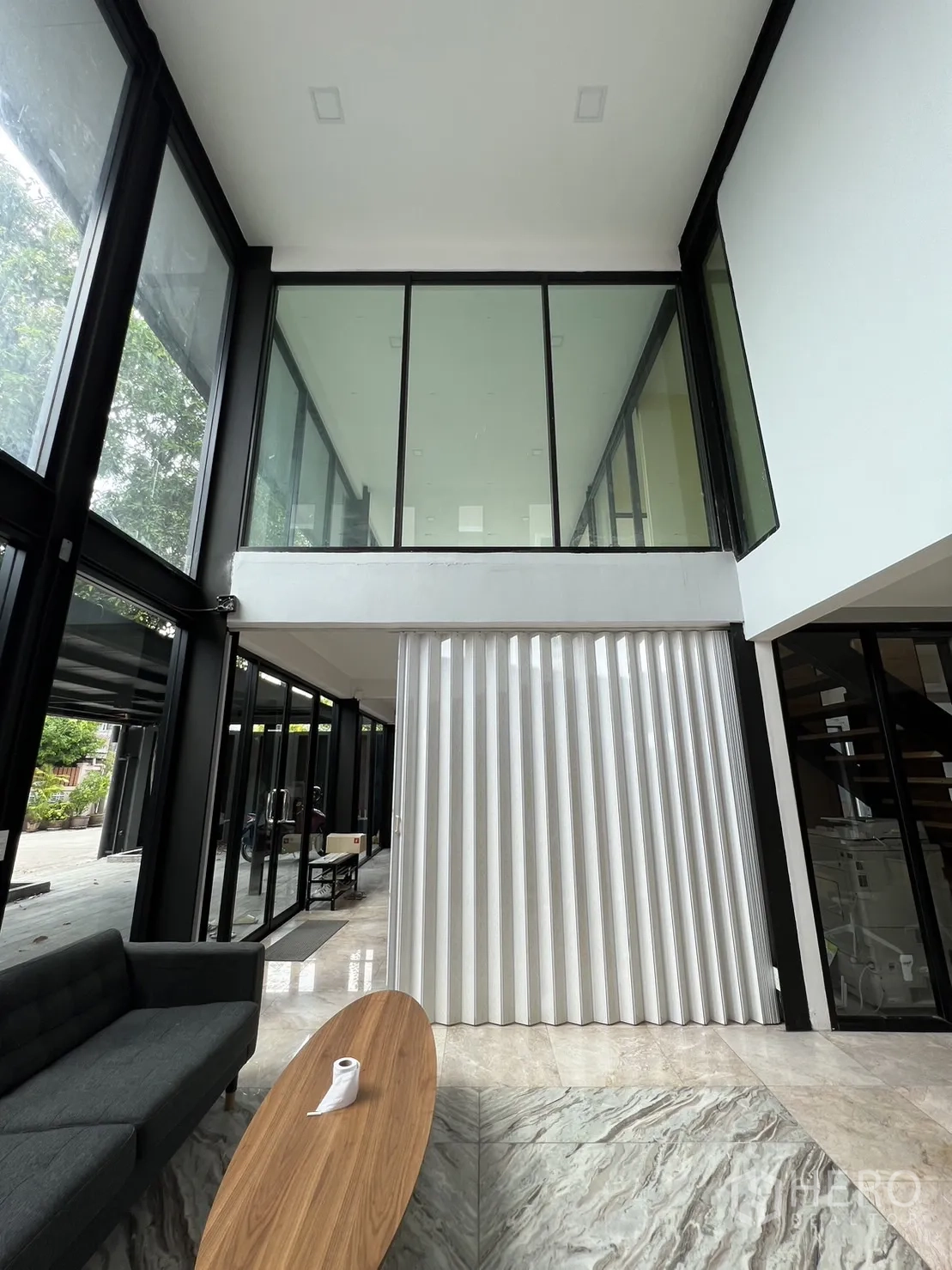 Detached House for rent or sale in Phra Khanong, Bangkok - View of mezzanine glass wall above the living area with large folding divider and coffee table.